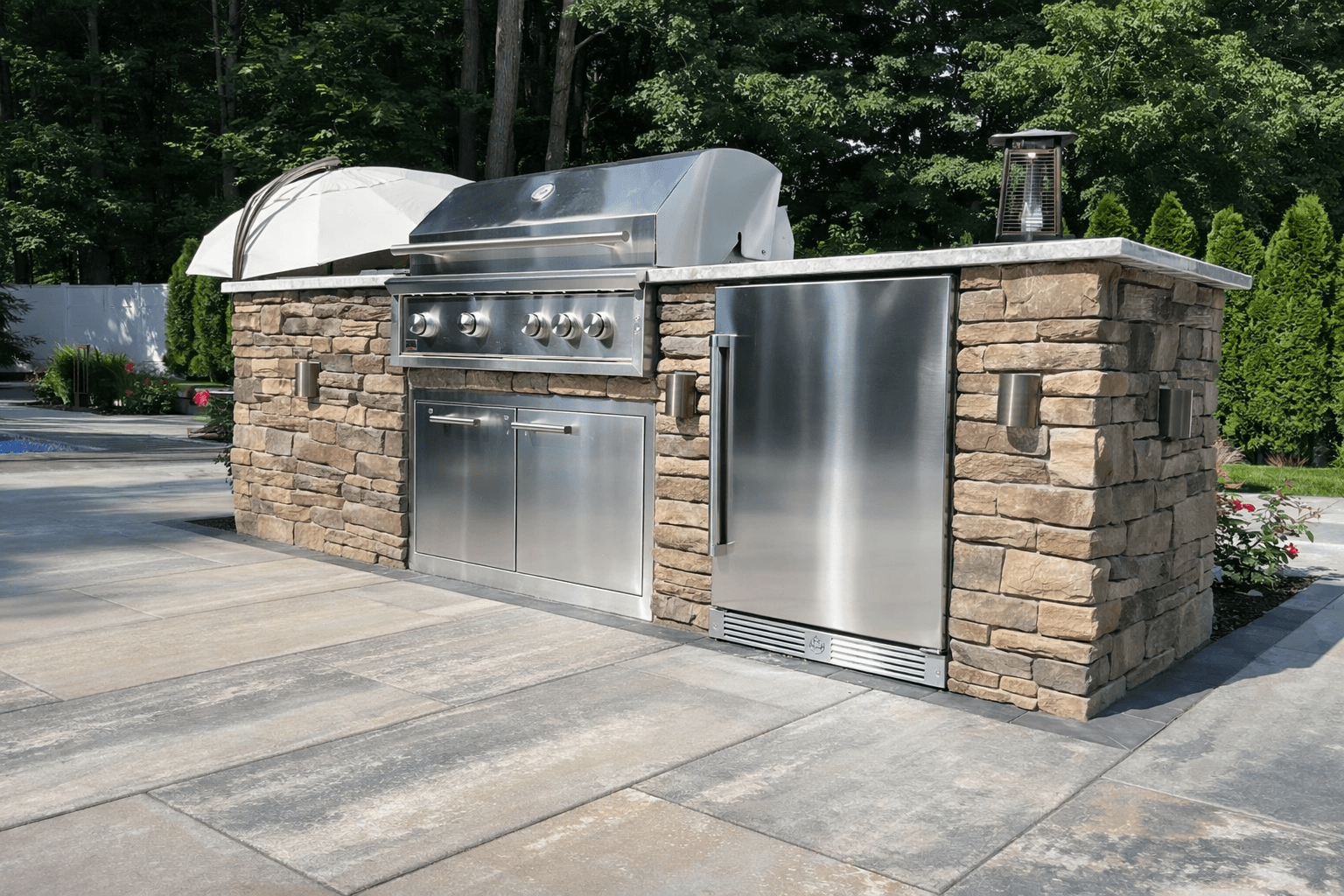 Outdoor kitchen with built-in grill, refrigerator, and stone paver patio