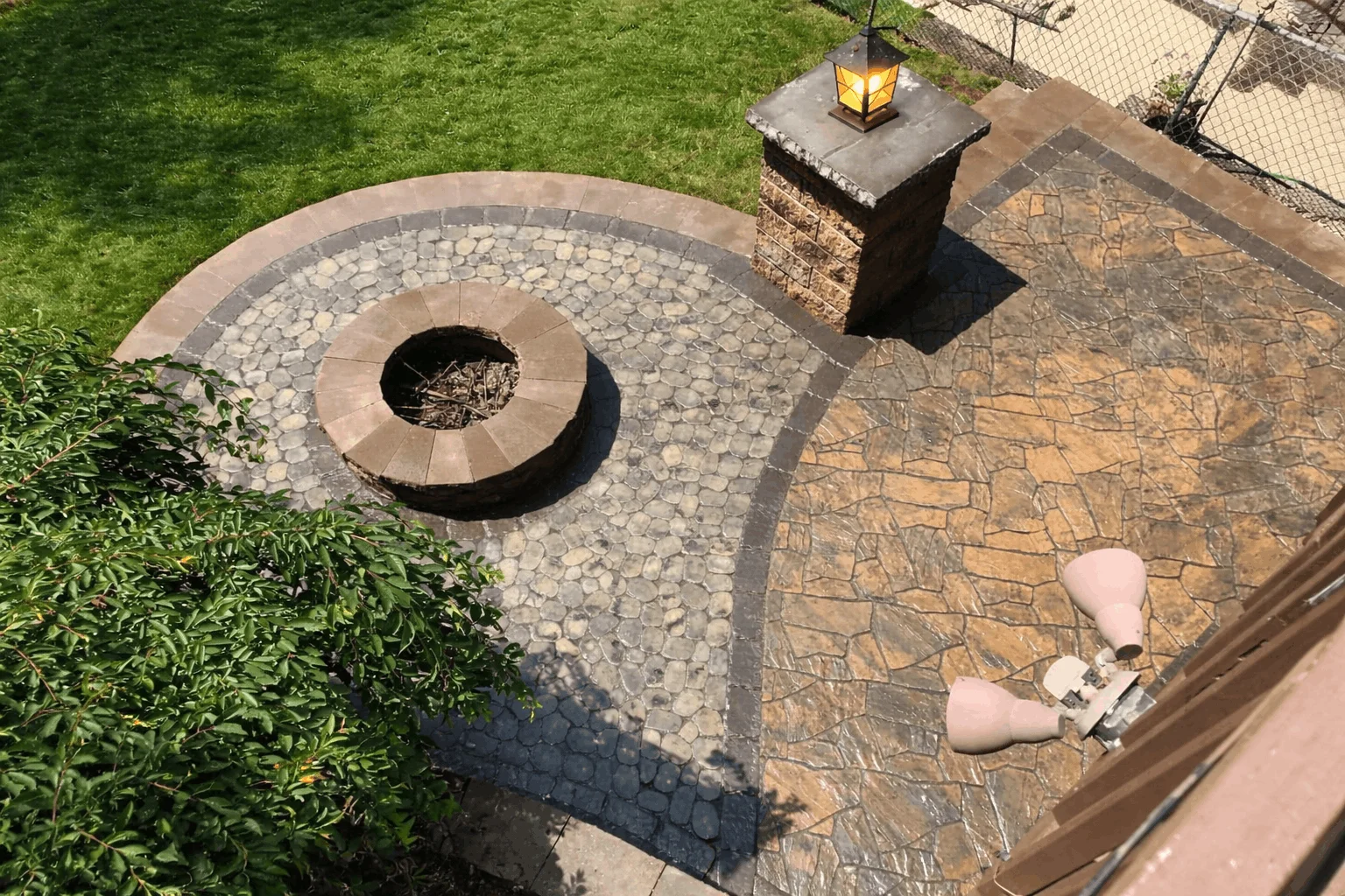Backyard patio featuring round fire pit, decorative stone inlay, and textured concrete surface