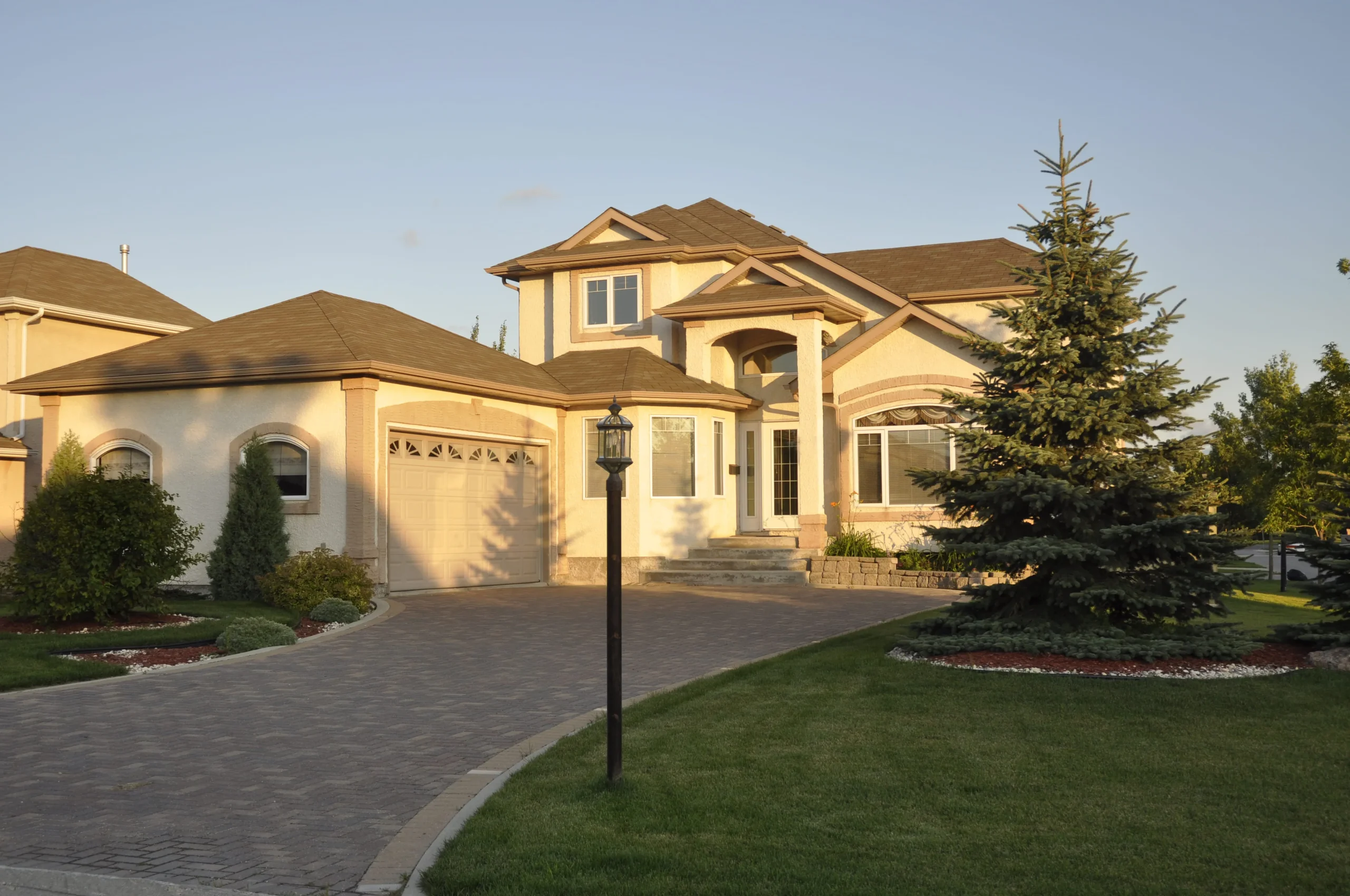 Front yard of a modern suburban house with driveway, lawn, and outdoor landscape lighting in New York.