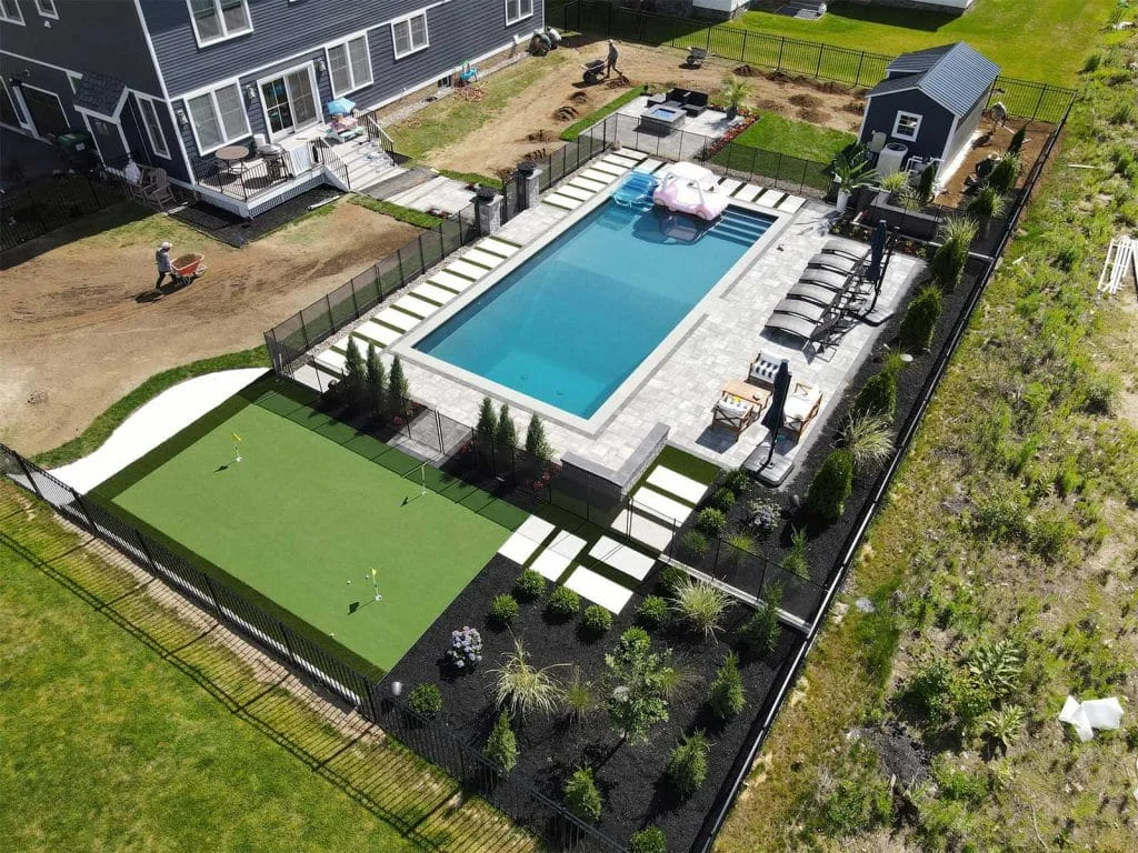 Overhead view of landscaped backyard featuring swimming pool, lounge chairs, and artificial putting green.