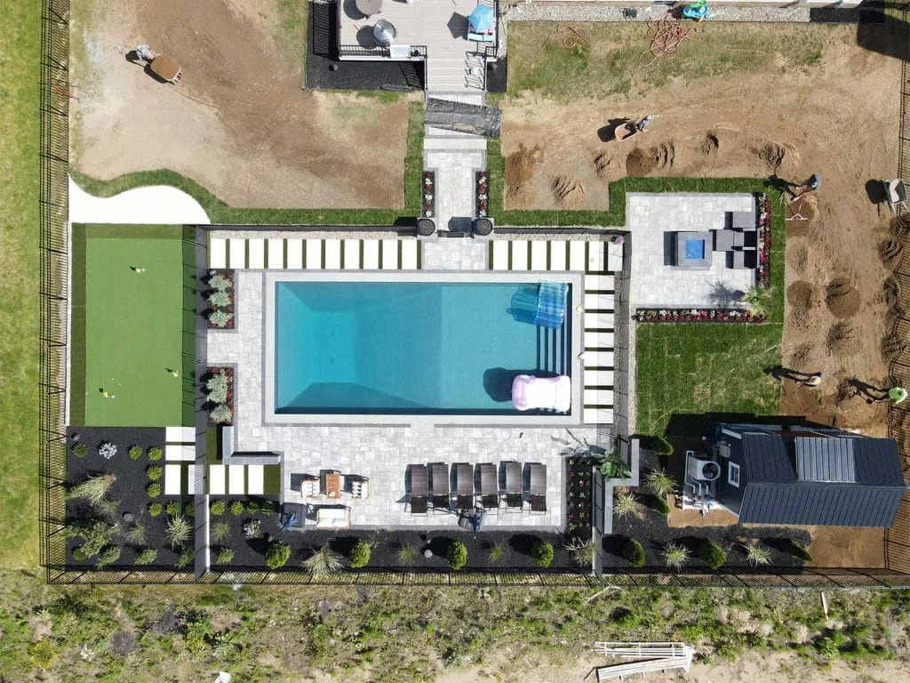 Bird's-eye view of a landscaped backyard with a pool, putting green, and a comfortable outdoor lounge area in New York.