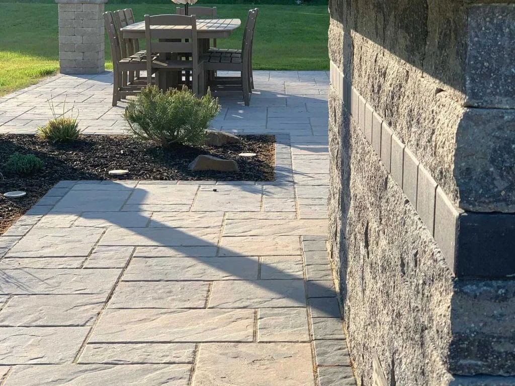 Stone paver walkway leading to outdoor dining patio with landscaped planting bed