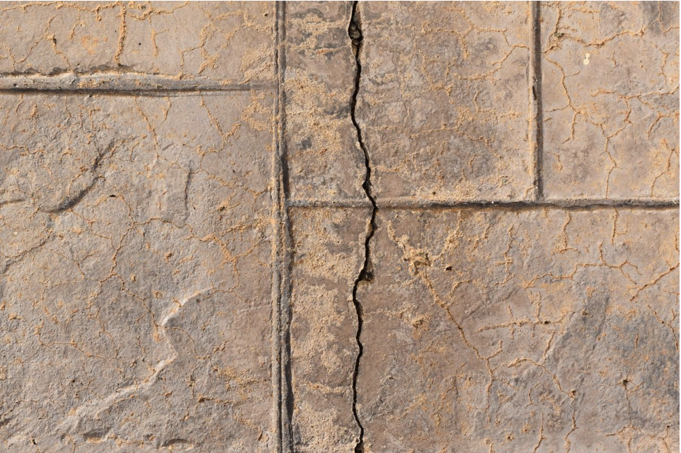 Detailed view of a large crack running through a weathered concrete slab indicating potential foundation damage.