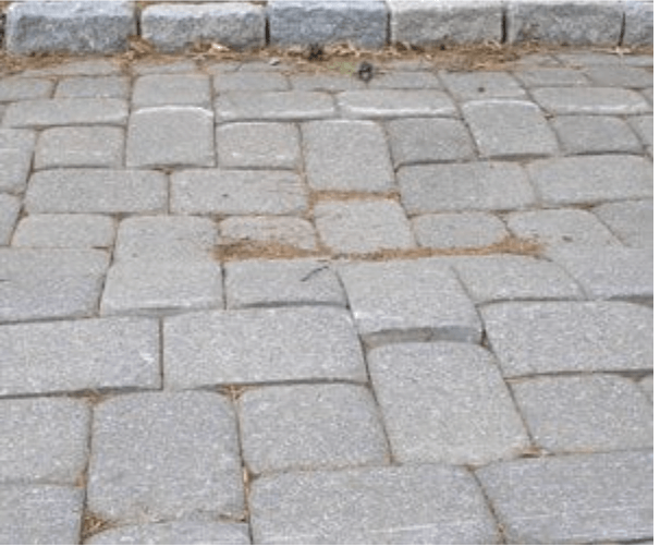 Sunken and uneven concrete pavers on a patio surface showing shifting stones and potential ground settling.